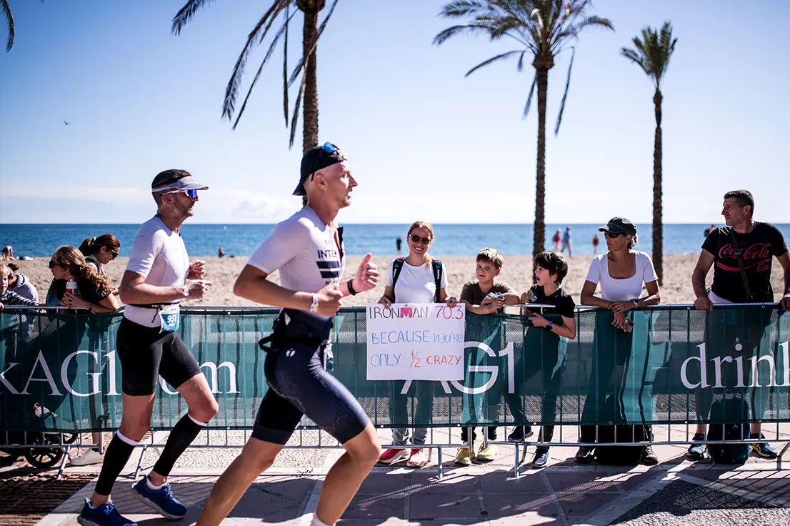 Atletas corriendo el recorrido a pie IRONMAN 70.3 Málaga a lo largo del paseo marítimo de Malagueta, con espectadores