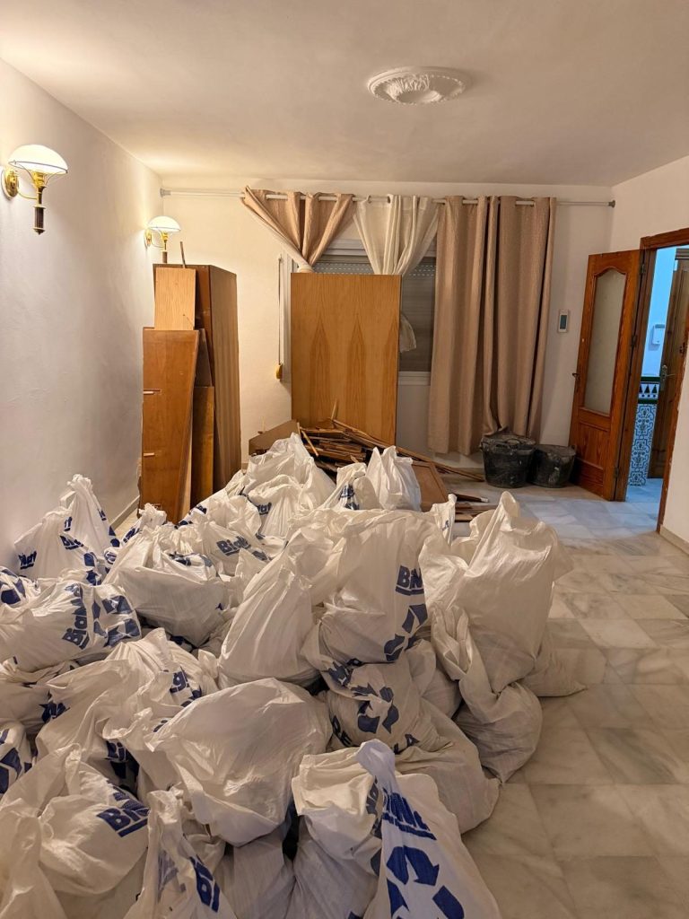 Sala de estar llena de bolsas de escombros durante la limpieza de la casa de pueblo de Cancelada
