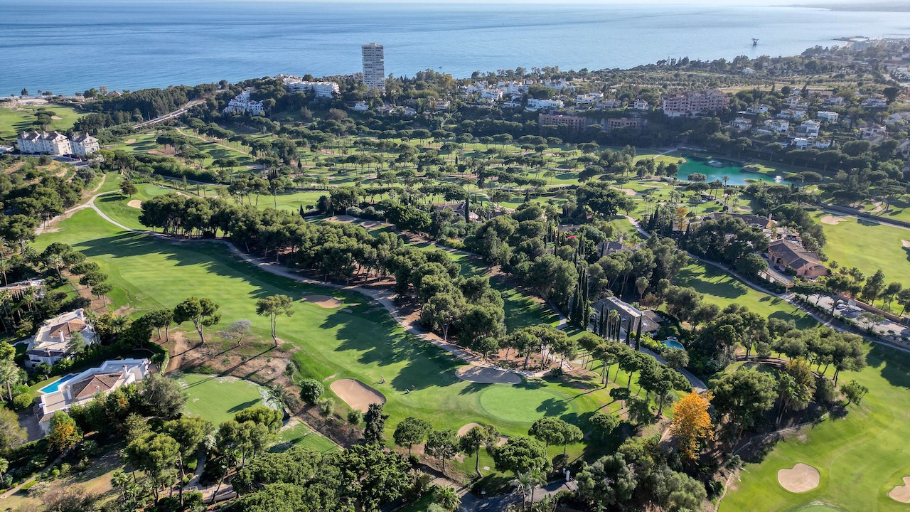 Vista aérea del campo de golf Río Real en Marbella, junto a la promoción Oakmond, con el mar al fondo