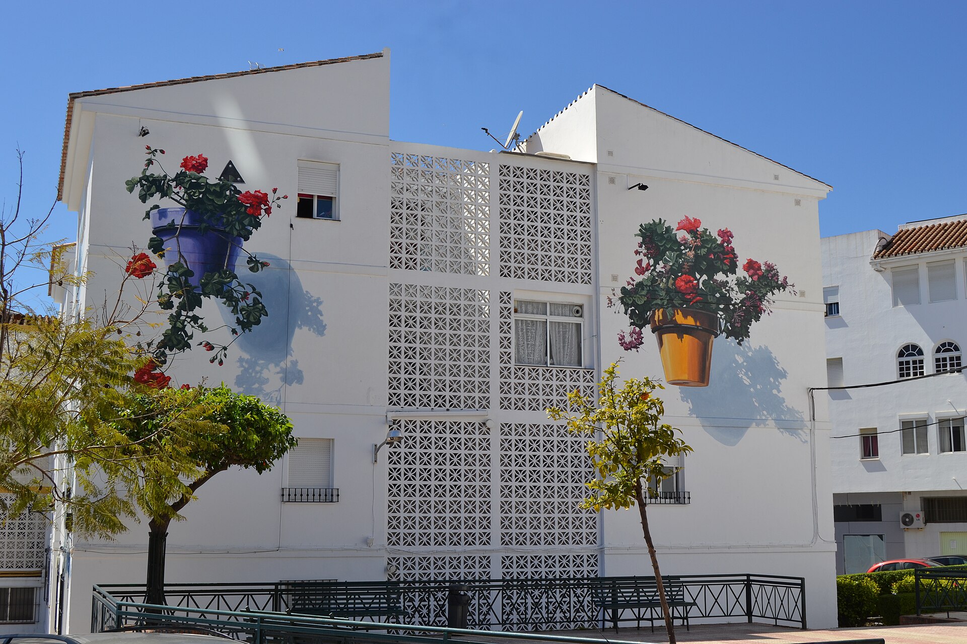 White Estepona old town building with a painted mural and flower pots