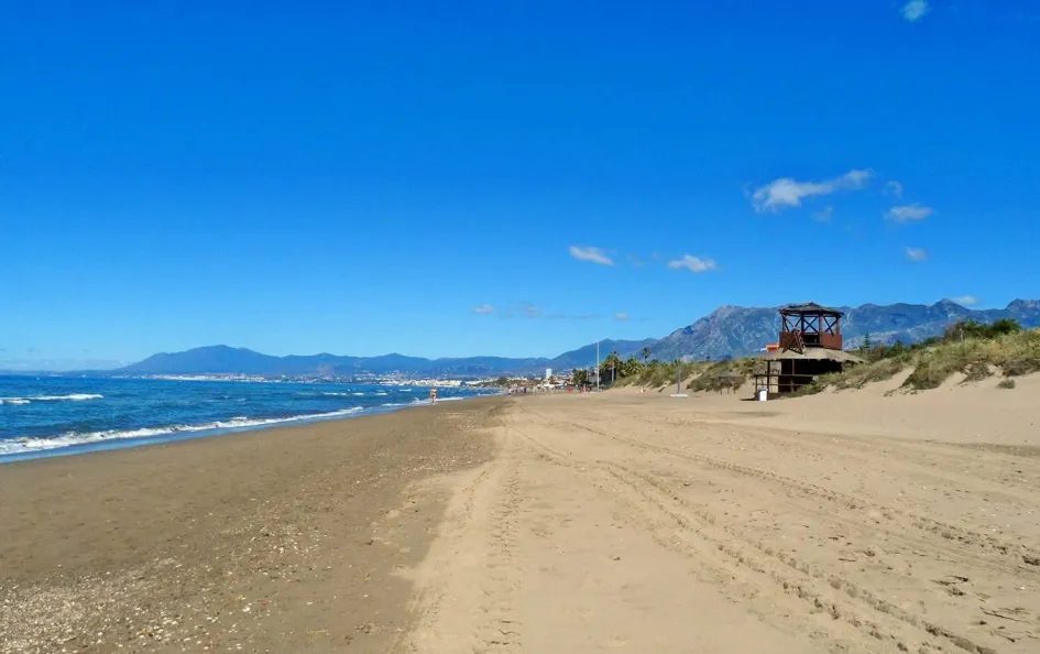 Real de Zaragoza beach in Las Chapas, Marbella East, with dunes and the Marbella skyline behind