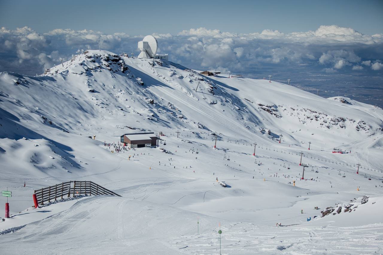 Skigebiet Borreguiles in der Sierra Nevada mit Liften, Pisten und Skifahrern unter blauem Himmel