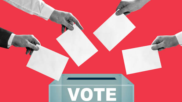 Hands placing ballots into a box marked vote, Spain general election 2026