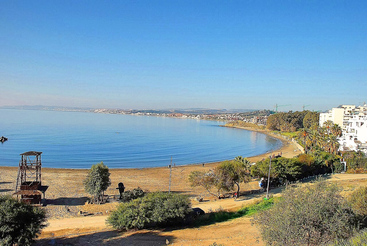 Vista sobre la bahía y Playa del Cristo en Estepona en un día de invierno despejado con una torre de salvavidas a la izquierda